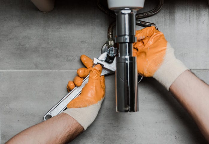 A plumber tightening a drain fitting
